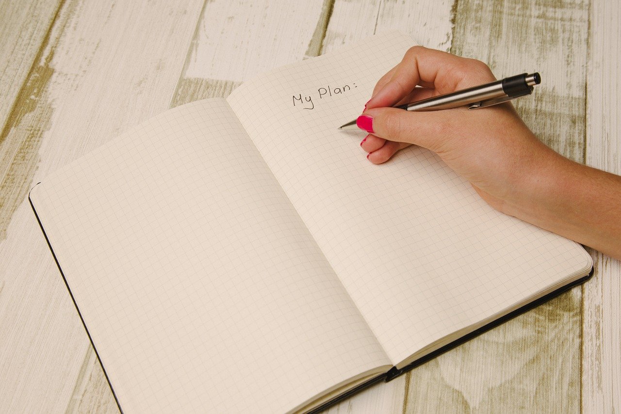 Kobieca ręka pisząca plan w notatniku