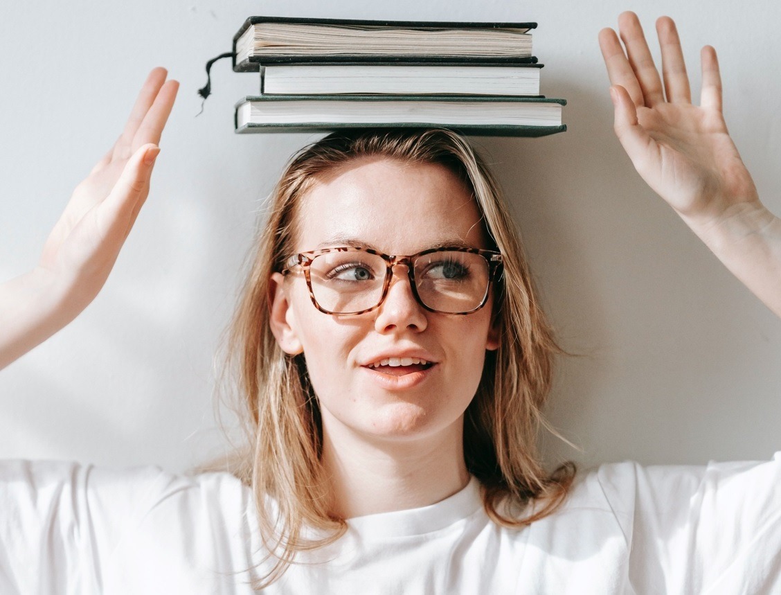 Dziewczyna w okularach z trzema książkami na głowie